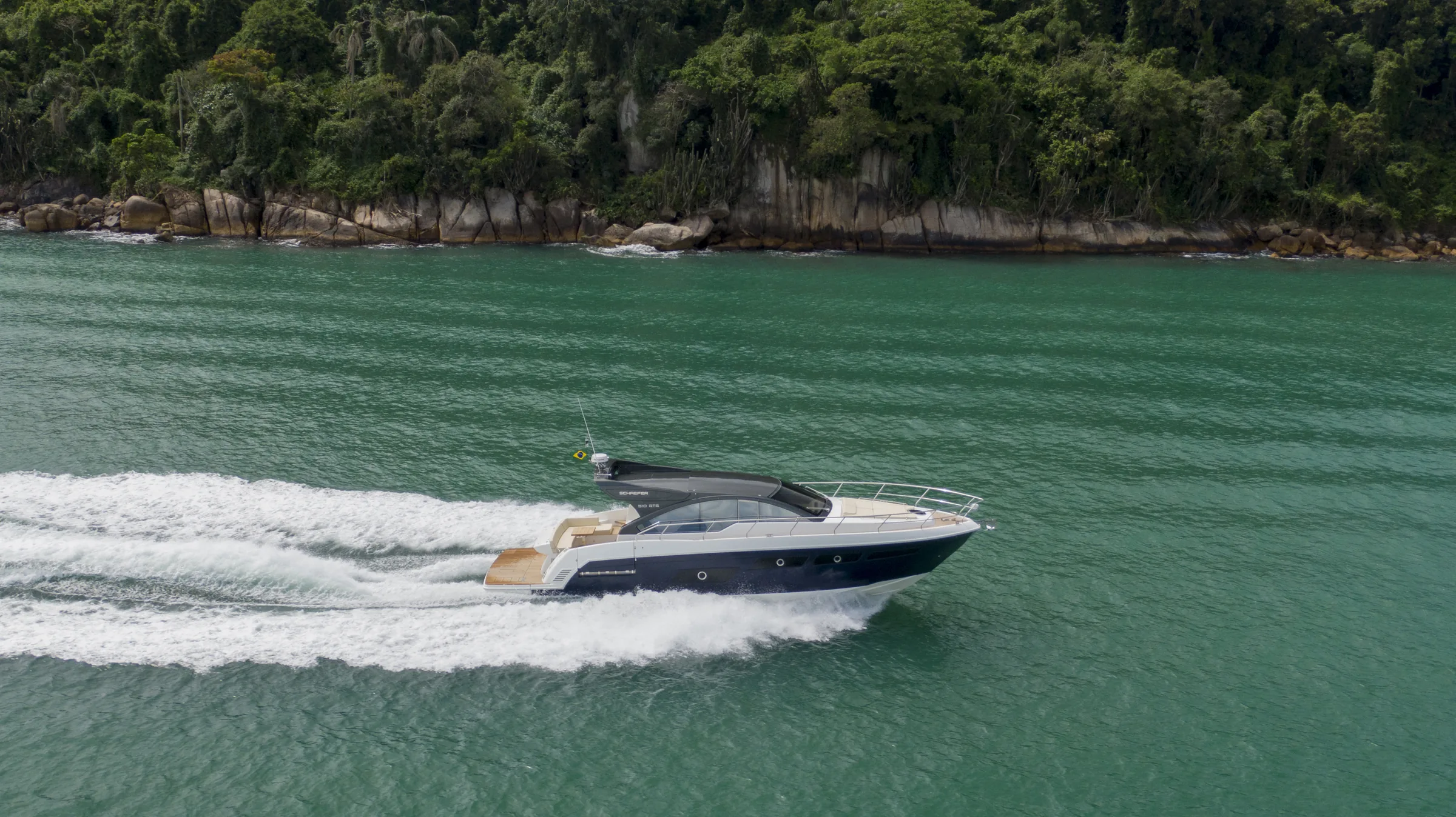 Schaefer 510 GTS running at speed along a green coastline