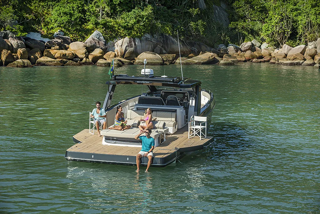 Schaefer V44 at anchor in a sheltered bay with both balconies open and guests swimming